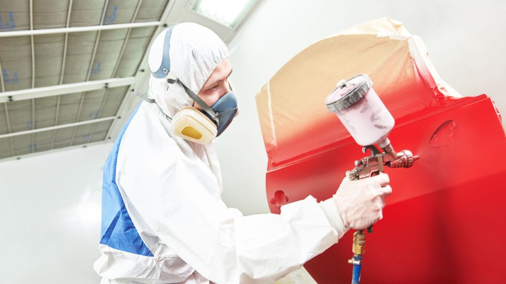 Man Spray Painting a Car Part
